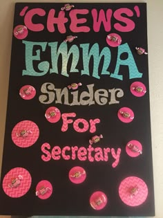 a black sign with pink and blue polka dots on it that says chees'elma slider for secretary