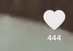 a white heart shaped object sitting on top of a gray surface with the number 444 below it