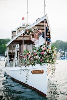 a bride and groom are standing on the bow of a boat with flowers in it