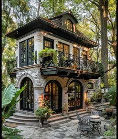 a small house with lots of windows and plants on the balcony, surrounded by greenery