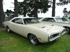 two old cars are parked in the grass