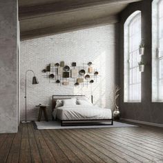 a bedroom with white brick walls and wooden flooring, along with a bed in front of a large window