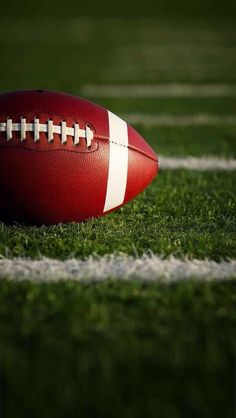 a close up of a football on the field with grass and white lines in the background