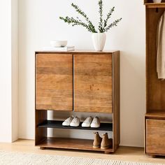 a wooden cabinet sitting next to a white vase filled with flowers and shoes on top of it