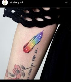 a woman's arm with a rainbow colored tattoo on the left side of her arm