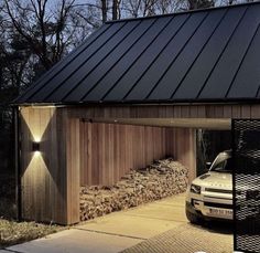 a car is parked in front of a garage with logs stacked on the side and under it