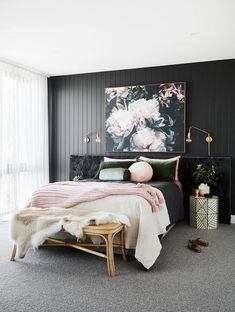 a black and white bedroom with pink flowers on the wall above the bed, along with an ottoman