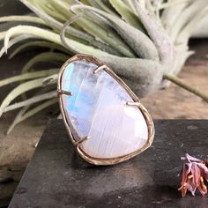 Inspired from the iridescent wings of a butterfly in flight, this milky rose cut moonstone with a blue-lavender flash is prong set in brass. Enjoy the mesmerizing flash of this magical stone with this ring! Height 1 1/4" Width 7/8" This piece is handmade-to-order, please allow 1 - 2 weeks to ship unless this piece is in stock. Each piece will vary slightly due to the uniqueness of the stones. All metal is nickel free. Butterfly In Flight, Iridescent Wings, Sunburst Ring, Rough Diamond Ring, Magic Stones, Moon And Star Ring, Magical Stones, Tanzanite Earrings