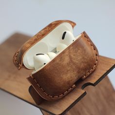 an apple airpods case sitting on top of a wooden stand with two heads in it