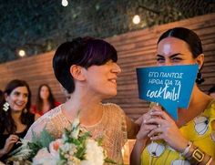 two women smile as they hold up a sign