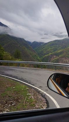 a car is driving down the road with mountains in the background