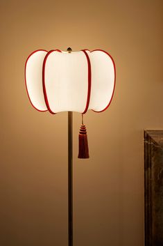 an apple shaped lamp with a red tassel on it's end and a white shade