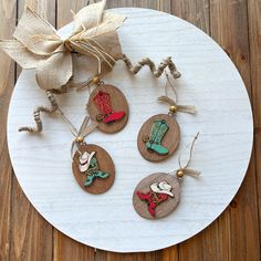 four wooden christmas ornaments are hanging on a white plate with burlocks and twine