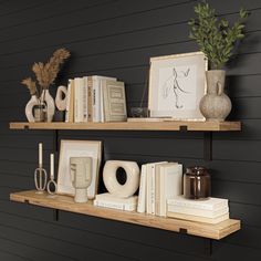 two wooden shelves with books, vases and other decorative items on them against a black wall