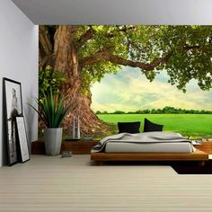 a bedroom with a large tree mural on the wall and bed in the foreground