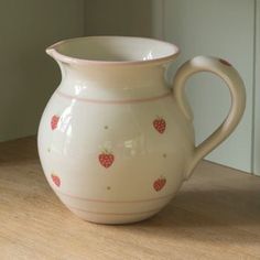 a white pitcher sitting on top of a wooden table