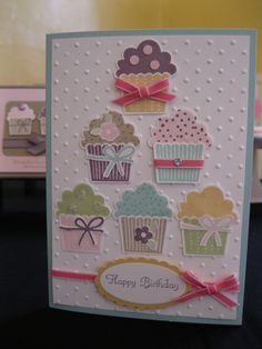 a birthday card with cupcakes and bows on the front, sitting on a table