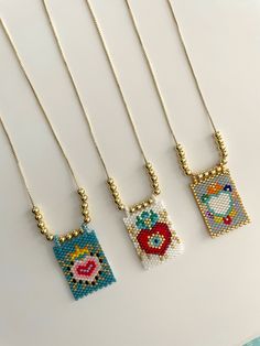 three necklaces with different designs on them sitting on top of a white table next to each other