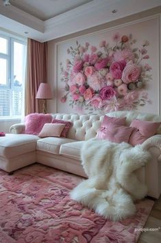 a living room decorated in pink and white with flowers on the wall above the couch