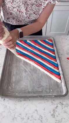 a woman is decorating a cake with red, white and blue icing