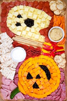 a platter filled with cheese, crackers and other food items that look like jack - o'- lantern faces