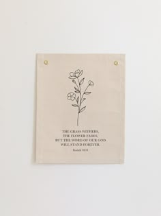 a white wall hanging with a black and white quote on it that says, the grass wishes, but the world of our god will not give us flowers