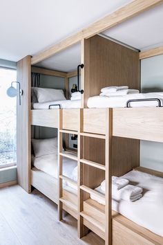 bunk beds are lined up in a room with wooden flooring and white linens