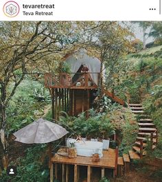 there is a tree house in the woods with an umbrella on it's deck