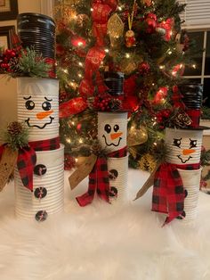 three snowmen made out of paper cups sitting in front of a christmas tree