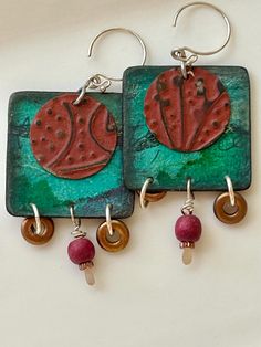 two earrings with red and green designs on them