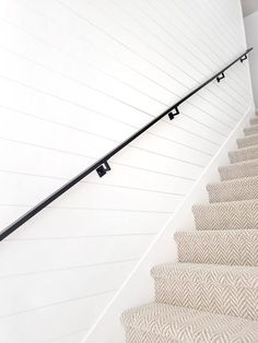 a stair case with metal handrails on the top and bottom, along with herringbone carpet