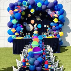 an outdoor space themed birthday party with balloons and tables set up for the event in front of a white brick wall