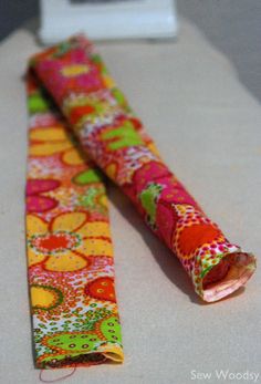 two rolls of colorful fabric sitting on top of a white toilet paper roll next to each other