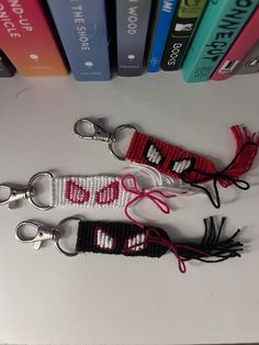 two red and white key chains sitting next to each other on top of a table