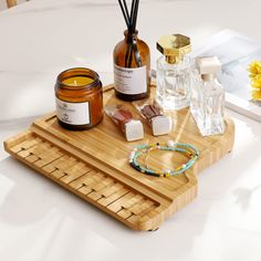 a wooden tray with candles, soaps and other items on it next to flowers