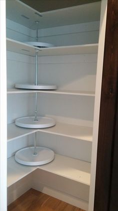 an empty pantry with white shelves and wood flooring