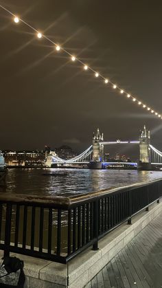 the bridge is lit up at night and has lights strung from it's sides