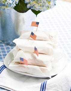 blue hydrangeas and white napkins on a table with a vase filled with flowers