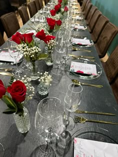 a long table is set with red roses and place settings for the guests to sit at