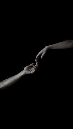 two hands reaching out towards each other in the dark