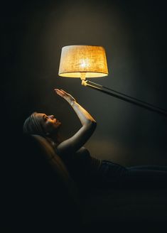 a woman laying on the floor next to a lamp that has a light on it