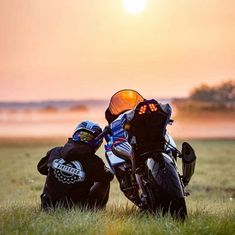 two motorcyclists are sitting in the grass with their bikes facing each other