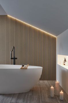 a white bath tub sitting in a bathroom next to a wall with wooden slats on it