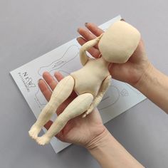 a person holding a stuffed animal in their left hand on top of a piece of paper