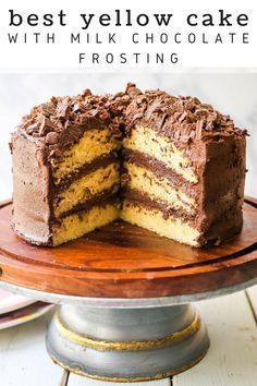 the best yellow cake with milk chocolate frosting is cut in half on a wooden platter