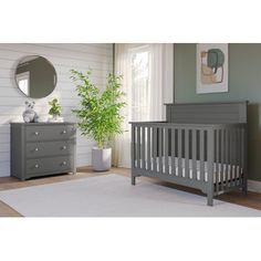 a baby's room with a crib, dresser and mirror