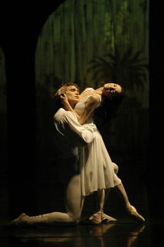 a man and woman dance together in the middle of a dark room with palm trees