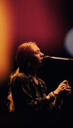 a woman singing into a microphone on stage