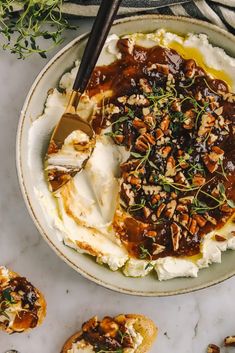 a bowl filled with mashed potatoes covered in gravy and topped with nuts