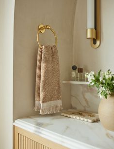 a towel hanging on the wall next to a vase with flowers